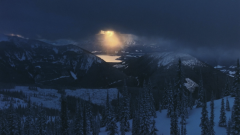 Paysage montagneux enneigé avec un rayon de soleil perçant les nuages