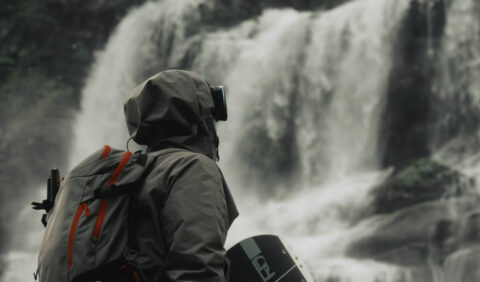Personne en tenue de randonnée regardant une cascade