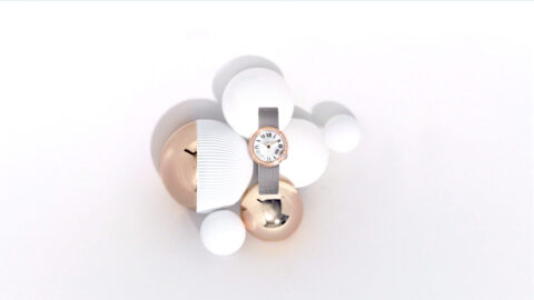 Montre élégante entourée de sphères blanches et dorées sur fond blanc