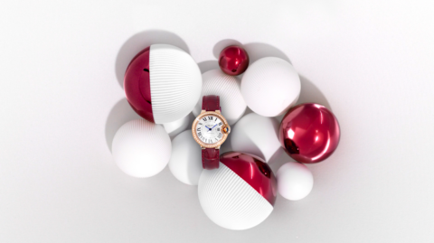 Montre élégante entourée de sphères blanches et rouges sur fond blanc