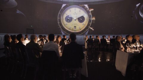 An elegant gala dinner under the watchful gaze of a gigantic wristwatch projection, in a multicanal sound design space.