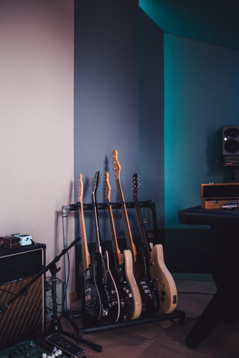 A collection of electric guitars lined up on a stand in a cozy music studio, awaiting the next jam session.