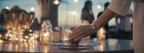 Main posant une pâtisserie avec une étincelle sur une table décorée