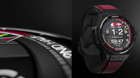 Montre connectée avec affichage de match et bracelet rouge sur fond noir.
