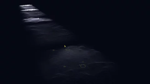 Route sombre avec petites sections éclairées et une petite lumière jaune au centre.