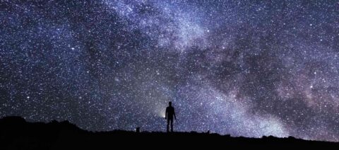 Silhouette d'une personne regardant un ciel étoilé rempli de la Voie lactée.