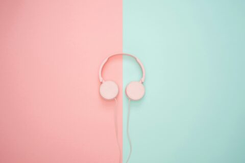 Casque audio rose sur un fond bicolore rose et bleu clair.